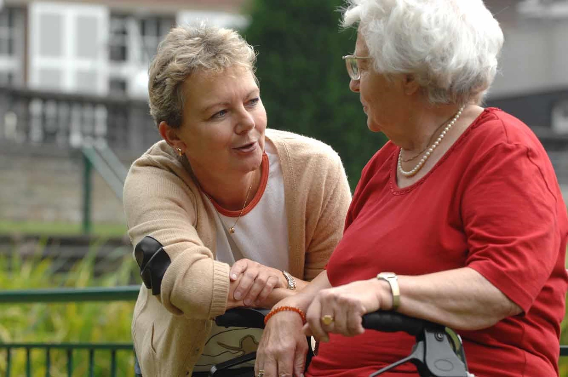 Begleiterin im Gespräch mit älterer Dame mit Rollator
